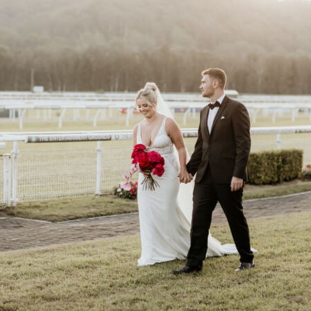 a man and woman holding hands and walking on grass